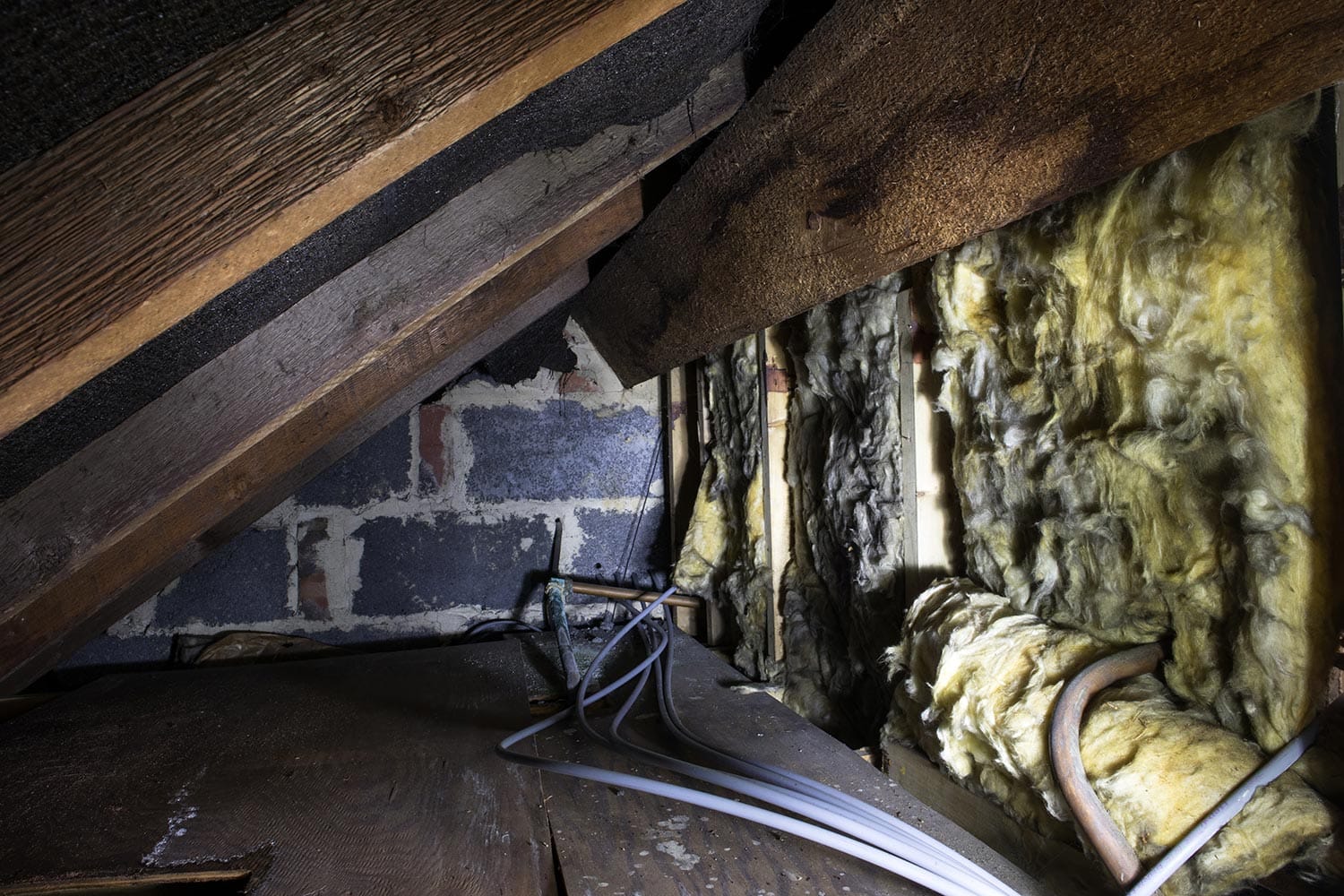Crawl space under the eves of a house showing old fibreglass insulation