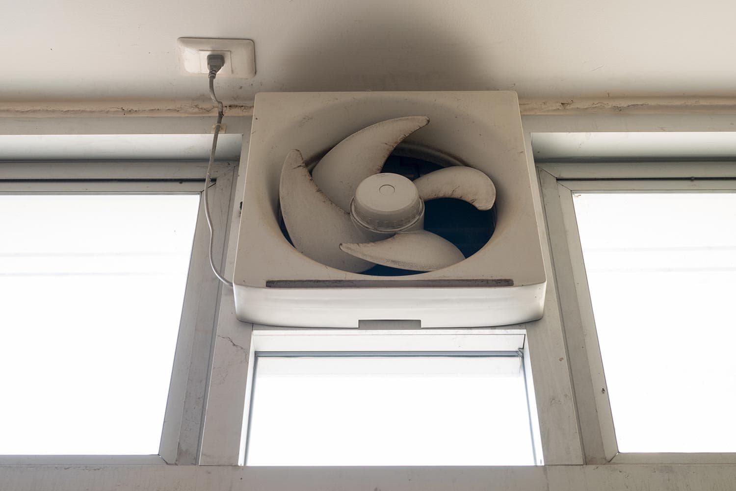 Dirty white ventilation fan in the window