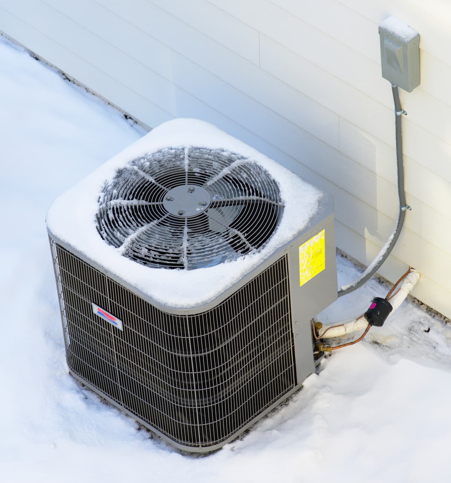 Exterior AC unit in the morning after a night of snowfall. Cooling unit of a townhouse.