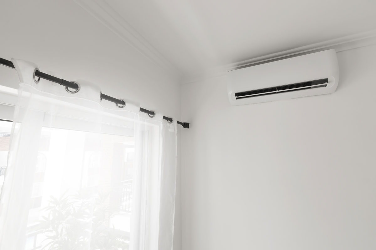 Flat air conditioner on white wall in room interior