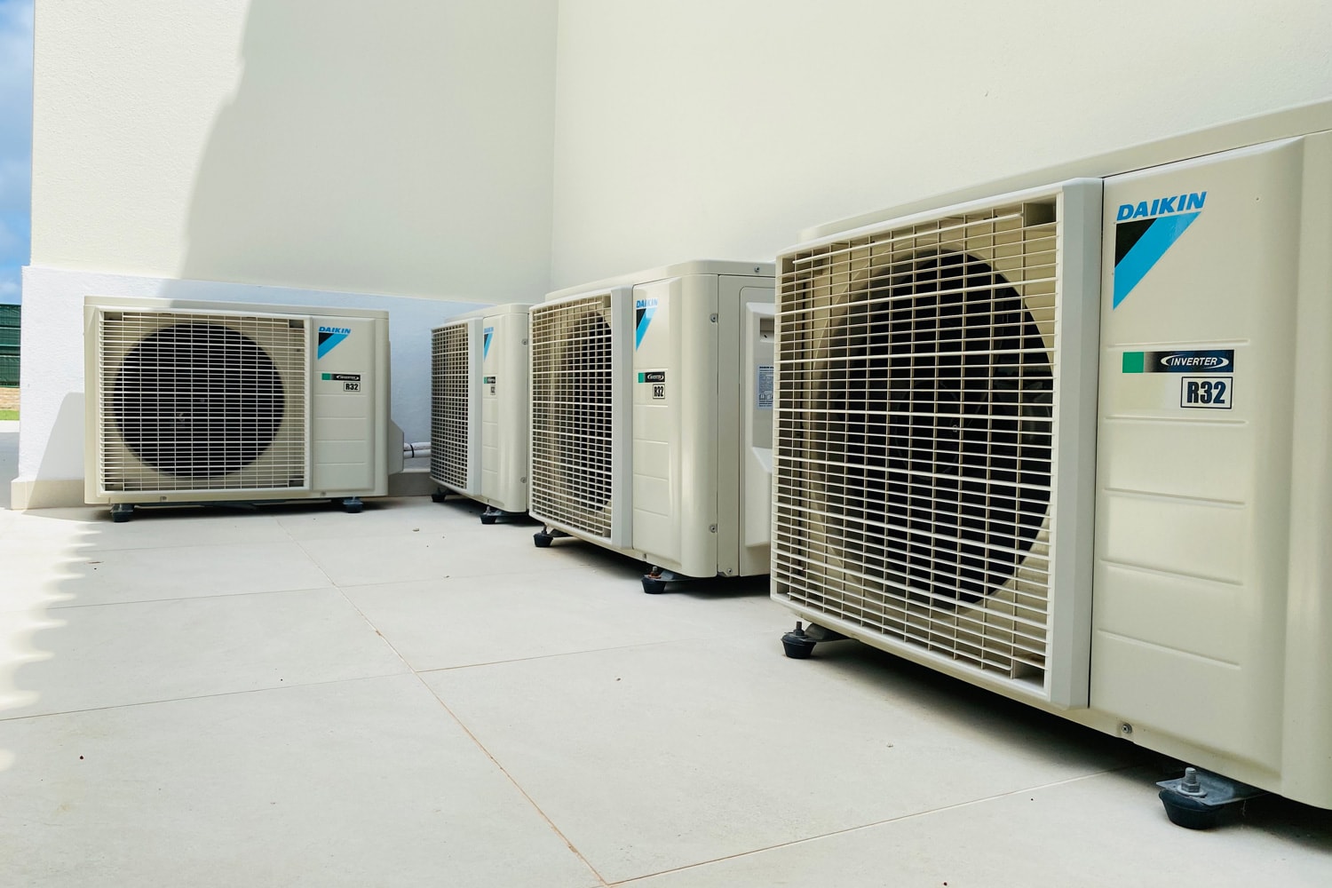 Four Daikin air conditioning units on a stone patio outside a residential home