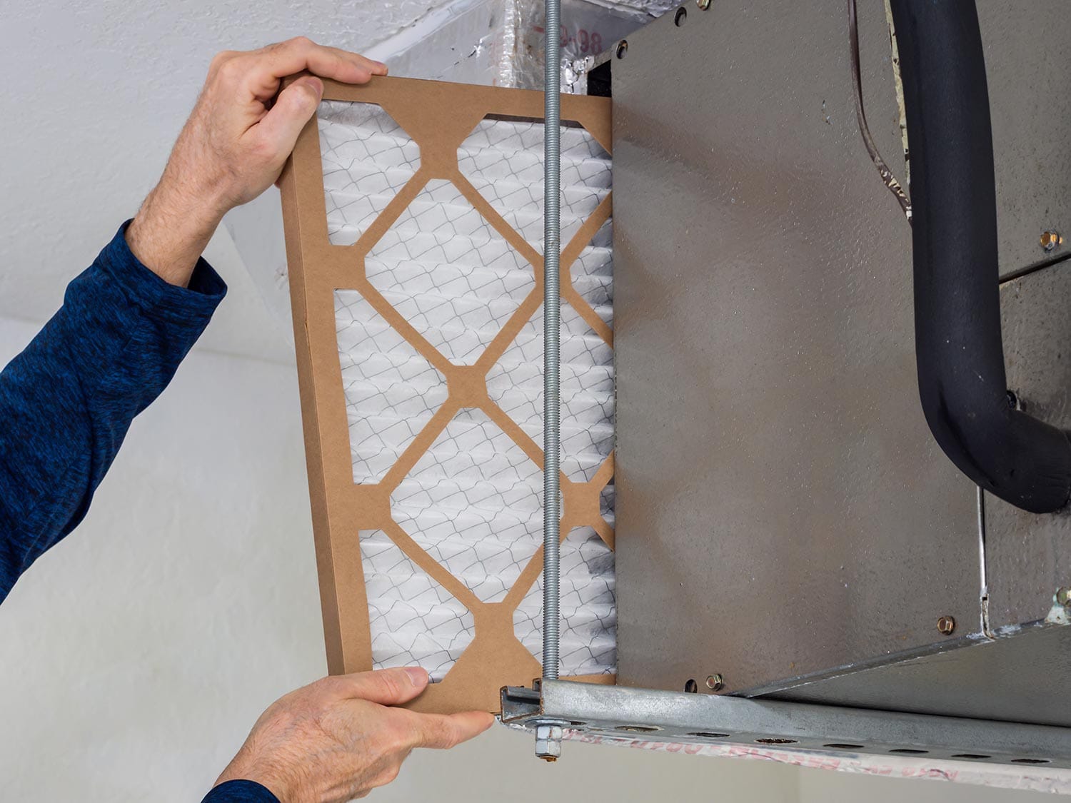 HVAC service technician changing dirty indoor air filter in residential heating and air conditioning system