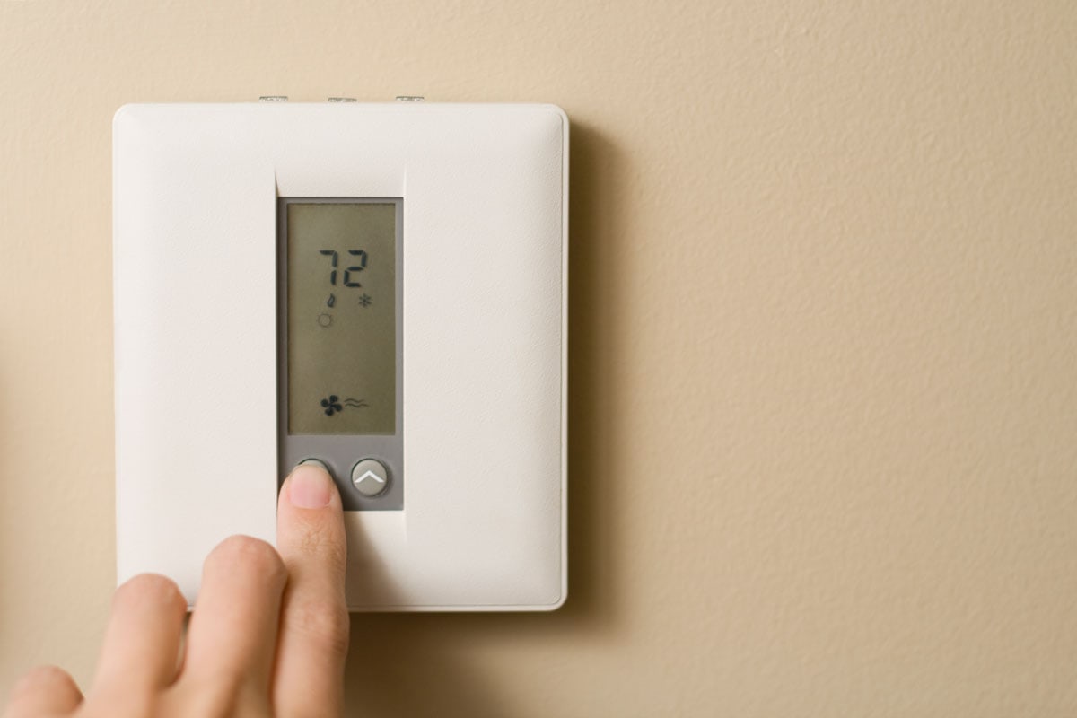 Homeowner adjusting the thermostat level to 72 degrees