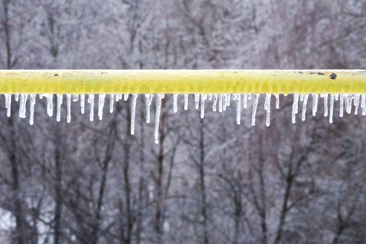 Icicles on the yellow gas pipe in winter weather