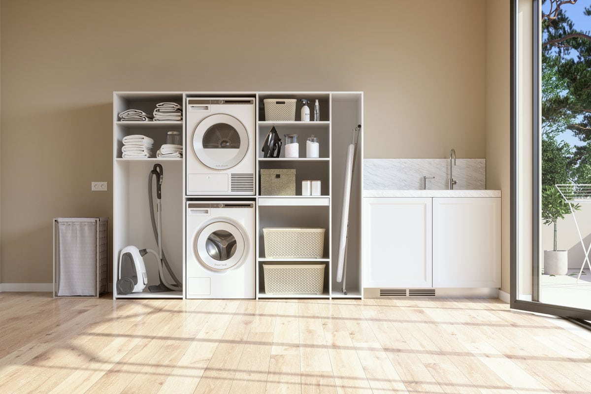 Laundry Room With Beige Wall And Parquet Floor With Washing Machine, Dryer, Laundry Basket And Folded Towels In The Cabinet