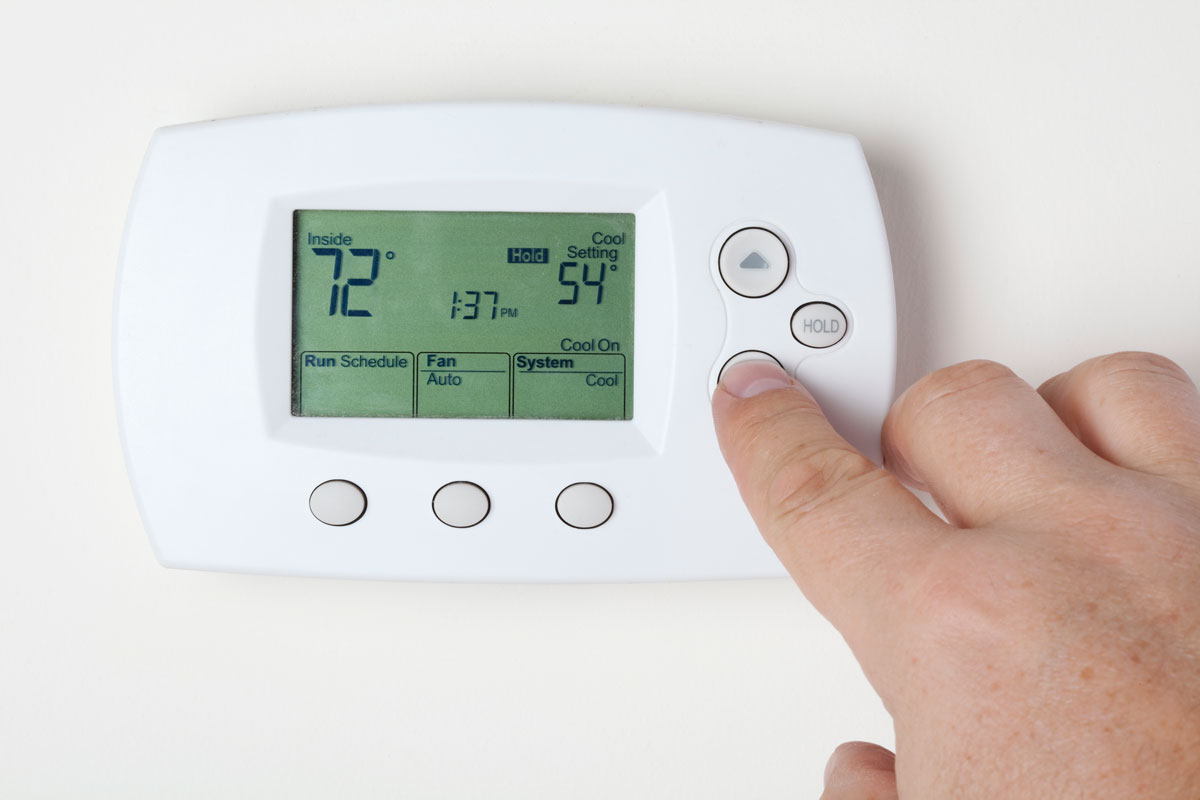 Man adjusting the thermostat level for the living room