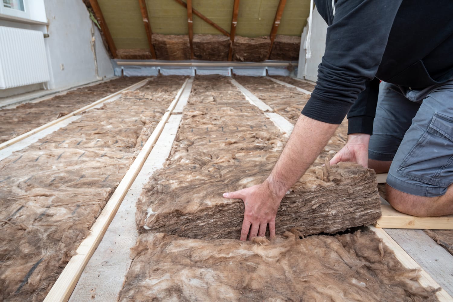 Man insulating the attic with rock wool.