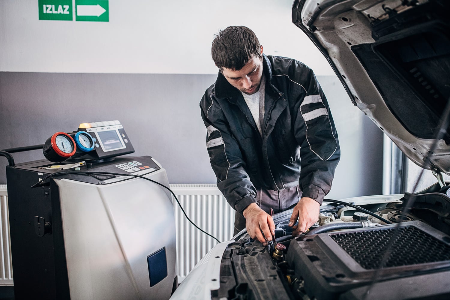 One man, mechanic recharging car air-condition in auto repair shop.