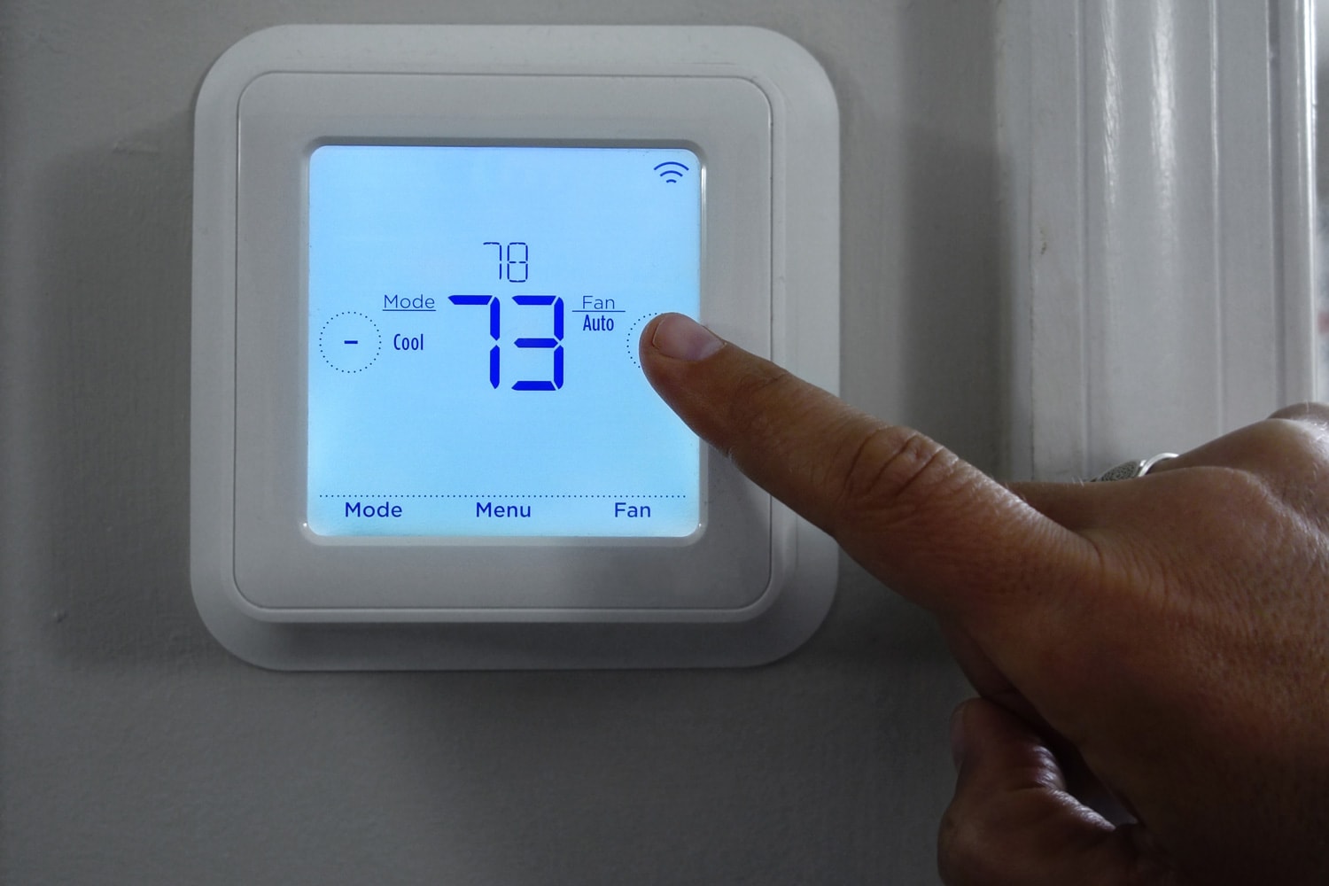 Person adjusting the home temperature on a smart thermostat