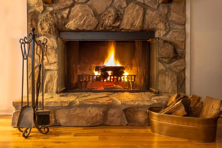 A stone fireplace with logs burning in a residential home, How Much Does Converting A Gas Fireplace To Wood Cost?