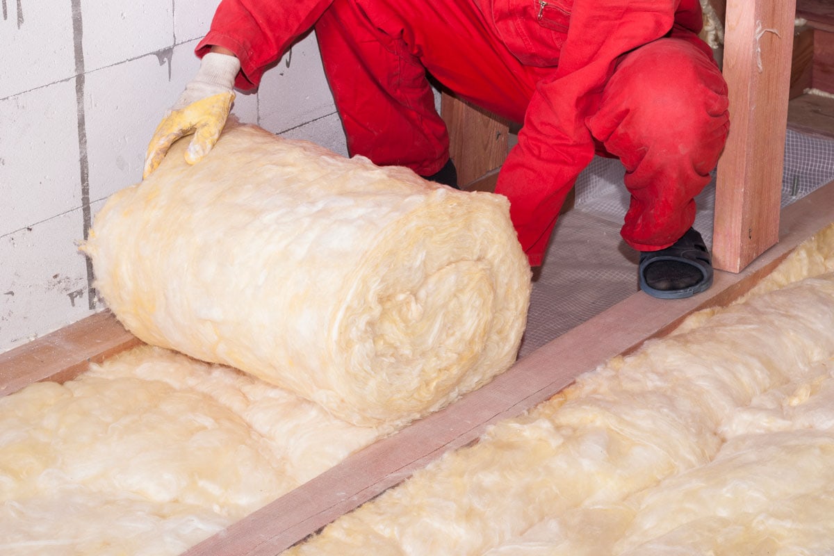 Technician unrolling a huge roll of fiberglass insulation