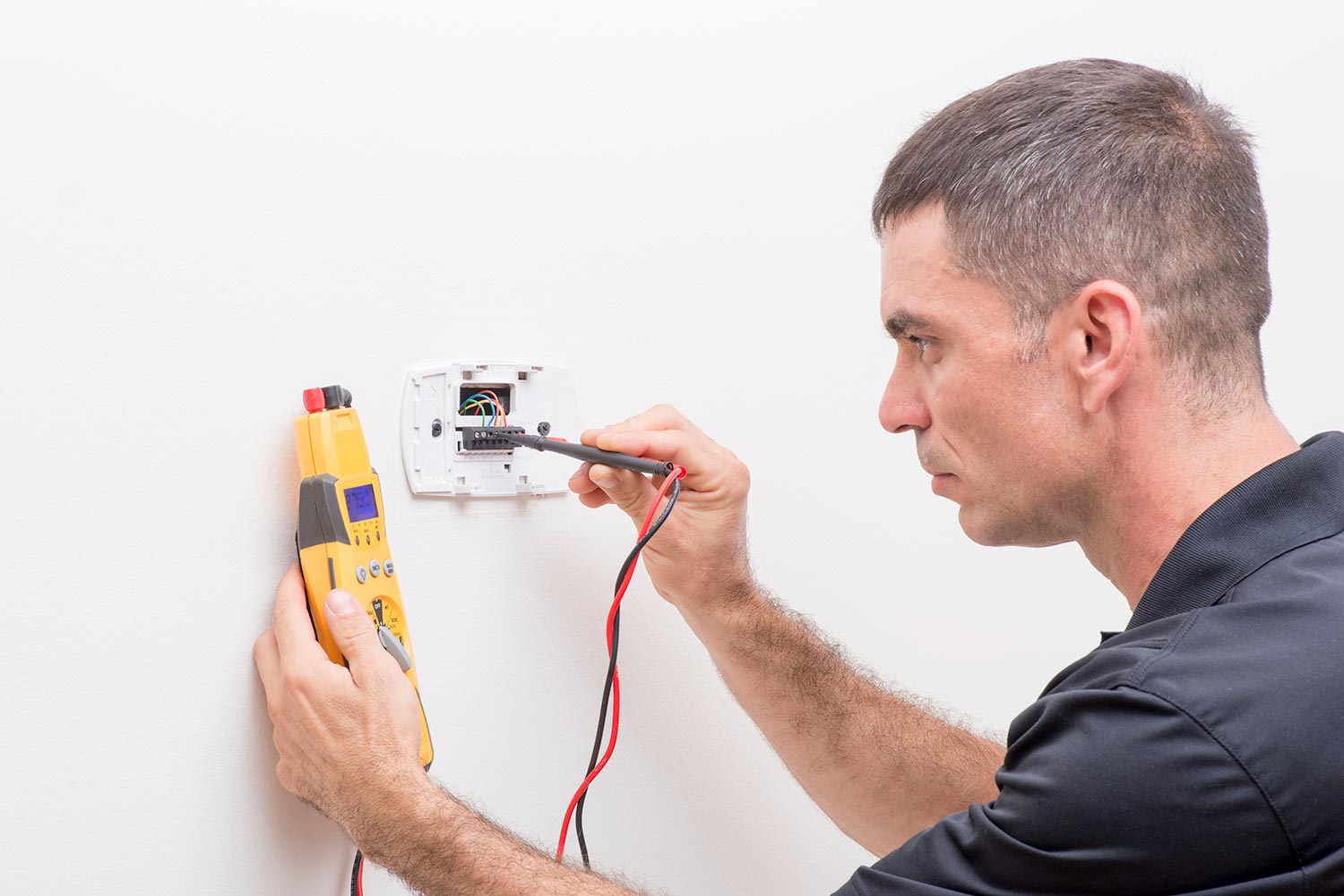 Trained HVAC technician checking troubleshooting a thermostat
