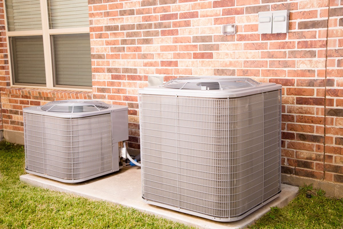 Two air conditioner units outside brick home
