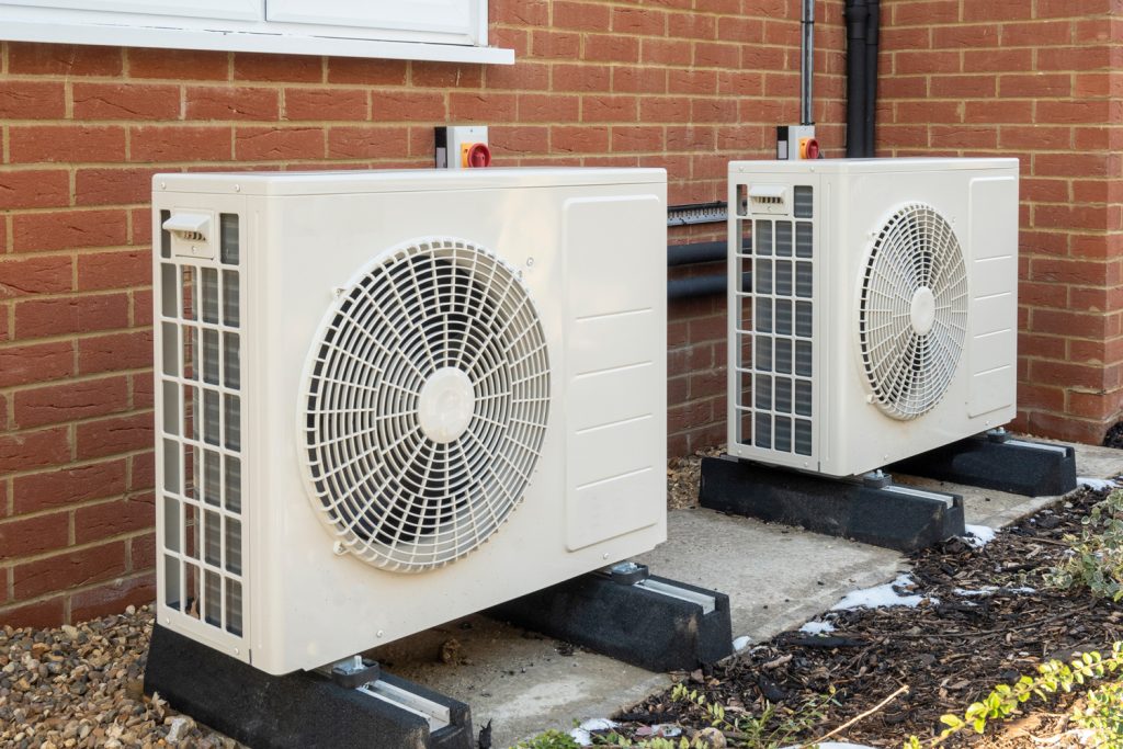 Two air source heat pumps installed on the exterior of a modern house