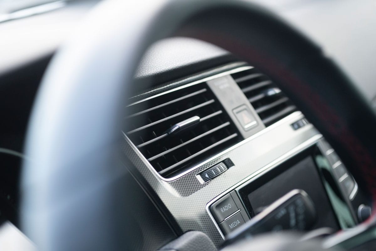 Up close photo of a car steering wheel and the car air conditioning unit