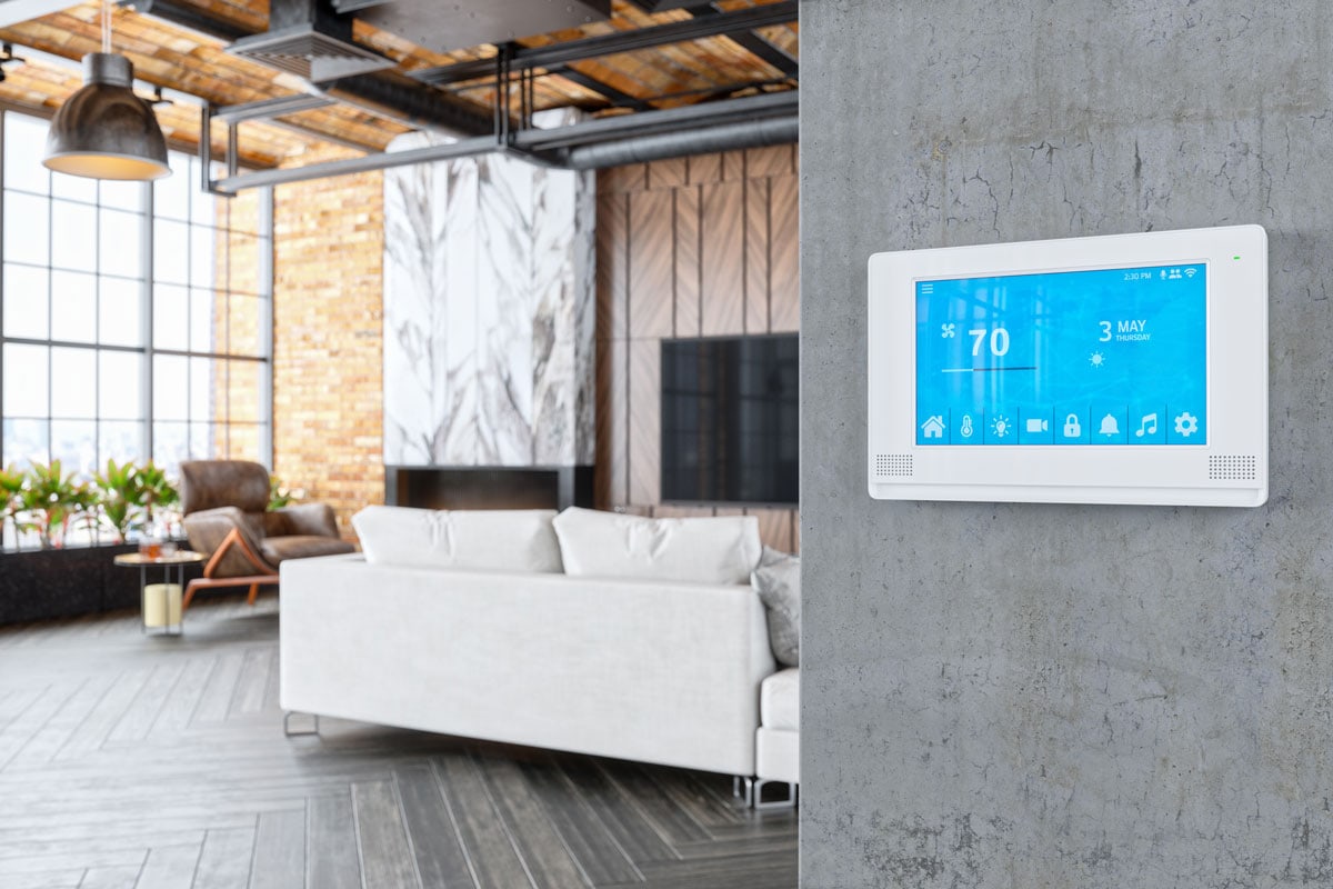 White digital thermostat mounted on a concrete wall