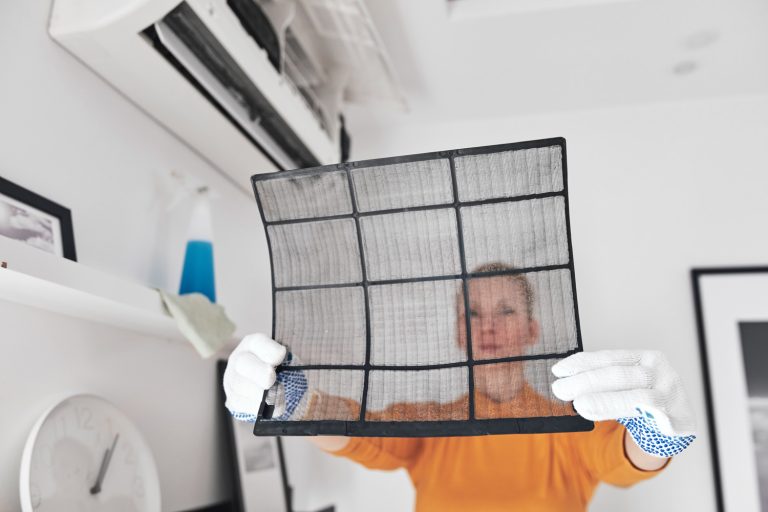Woman cleaning aircon filters indoor unit at home - How To Clean A Carrier Air Conditioner Filter