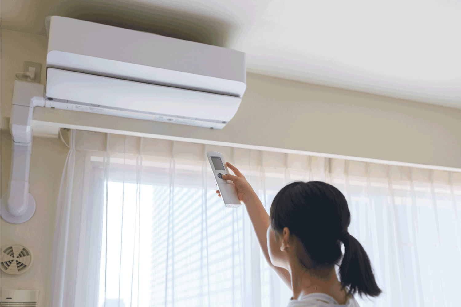 Woman control air conditioner power on