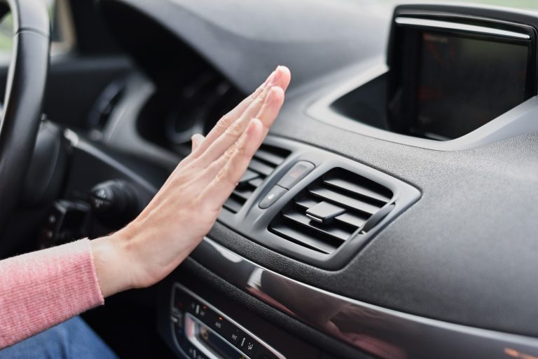 Woman hand on air conditioner ventilation grille in car. Climate control panel - Does Outside Temperature Affect Car Air Conditioner
