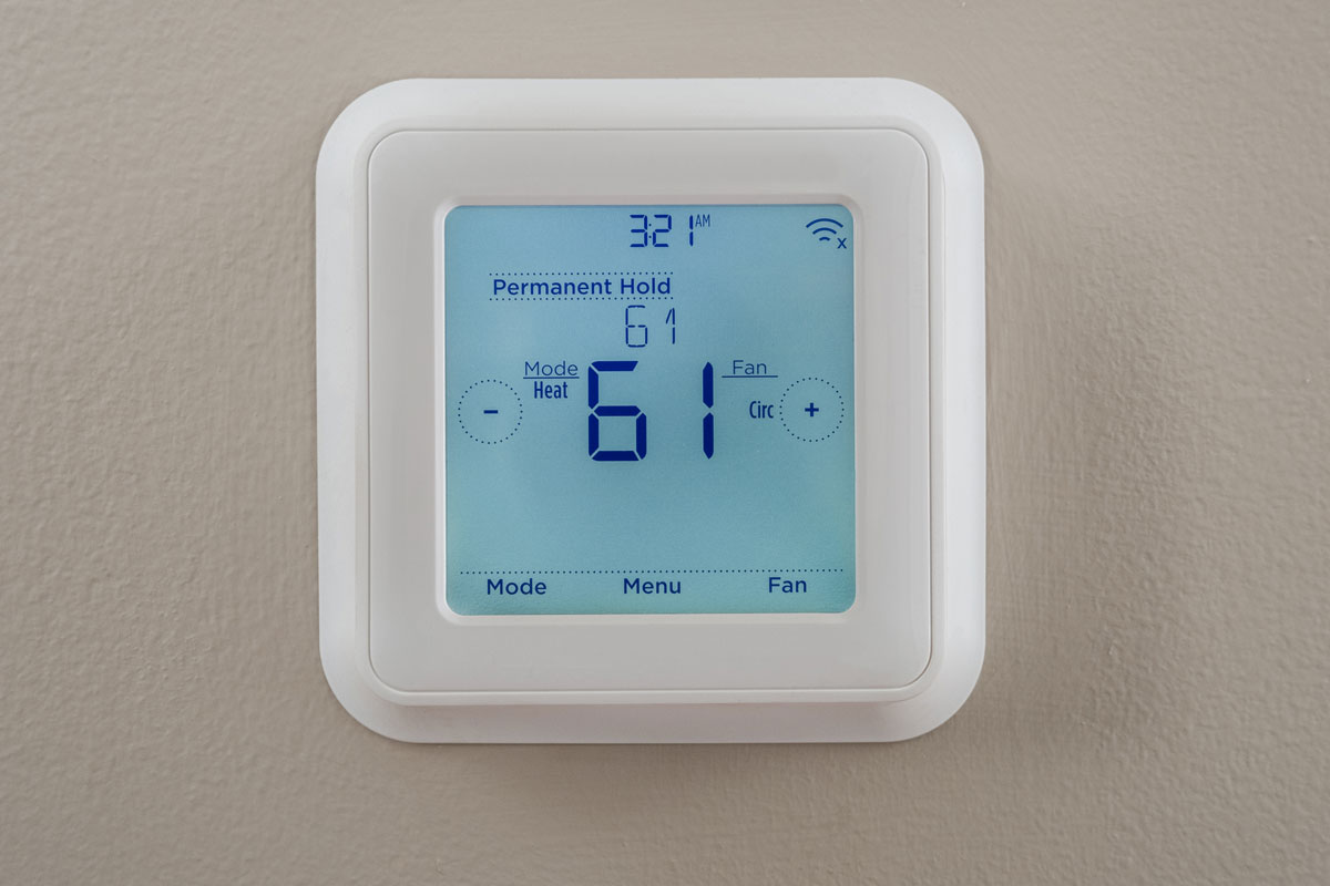 a modern residential programmable heating and cooling thermostat mounted on a wall