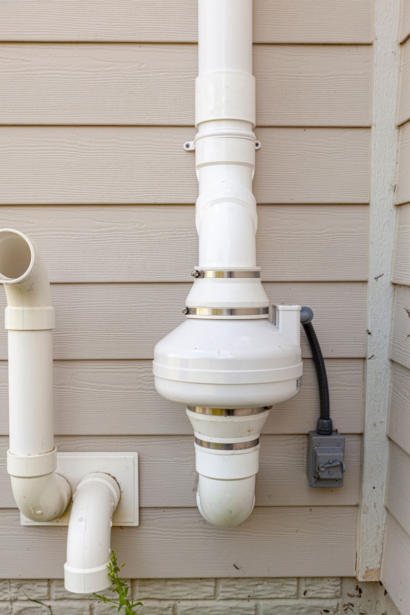 A Radon mitigation pipe on the wall of house