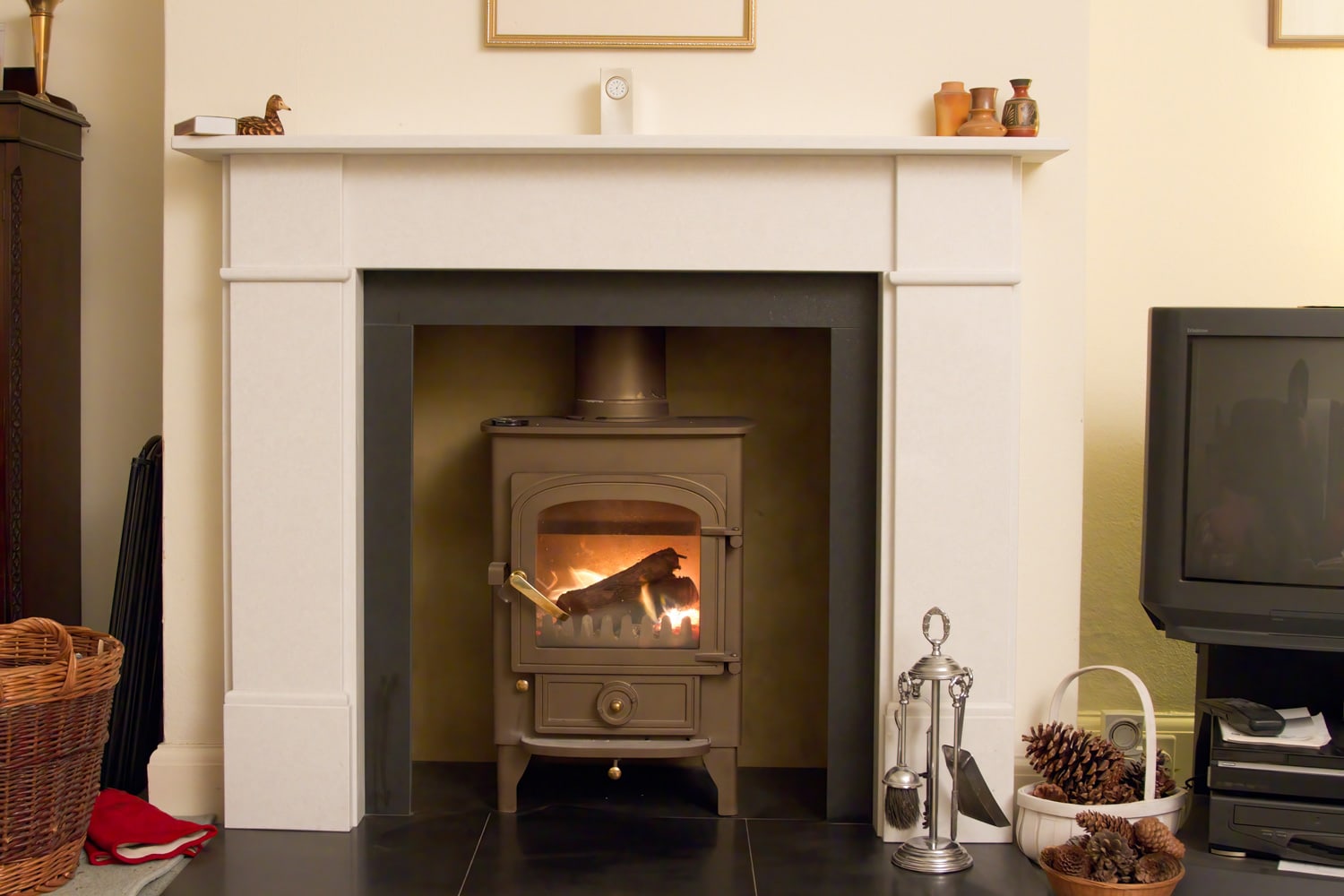 A cast iron wood burner, with a flue alight giving out a warm glow in a living room