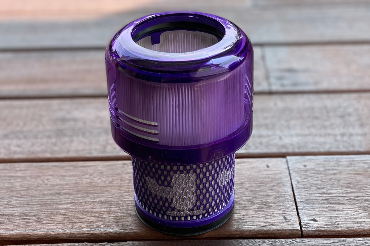 A close up view of Dyson cordless vacuum HEPA filter head on a wooden floor
