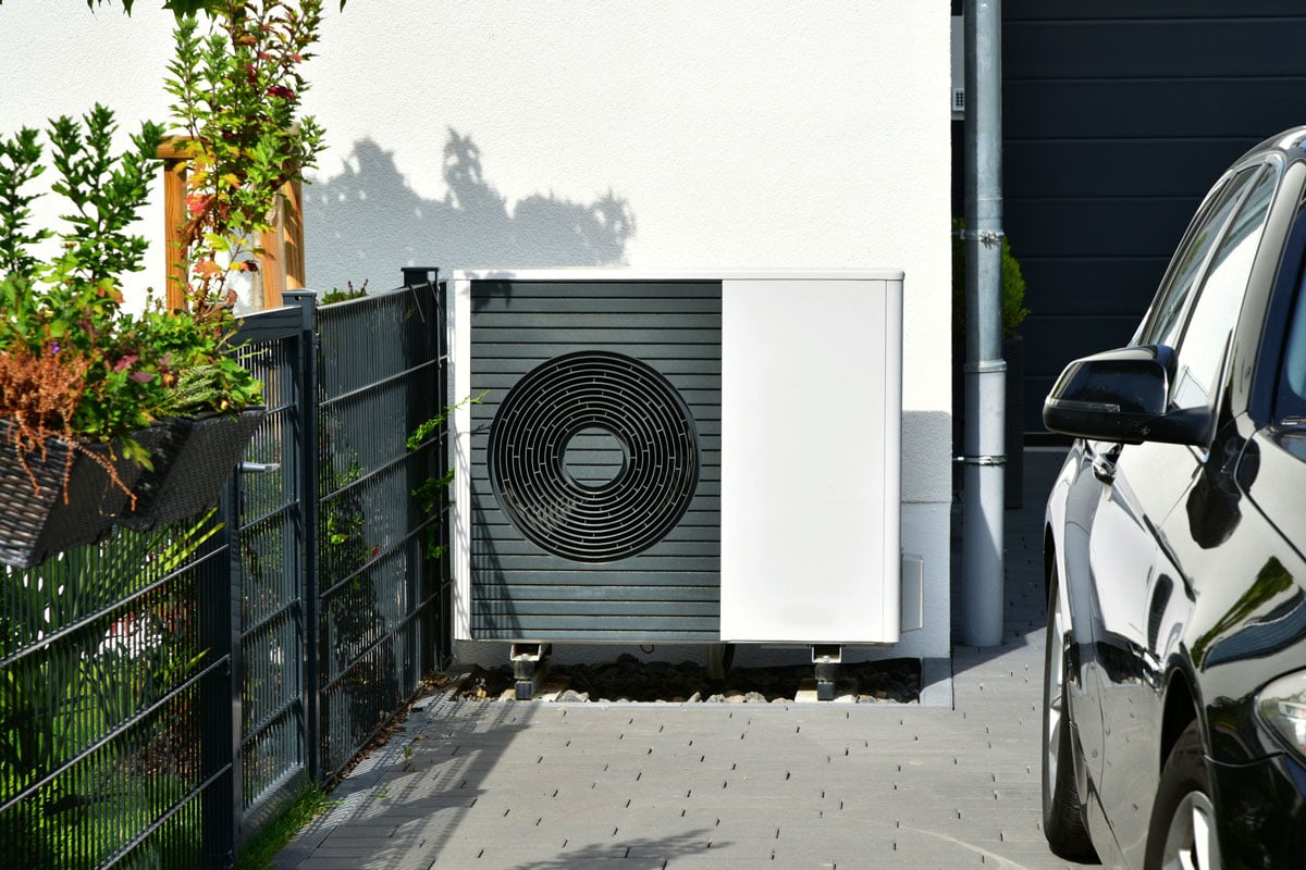 A heat pump mounted near the driveway