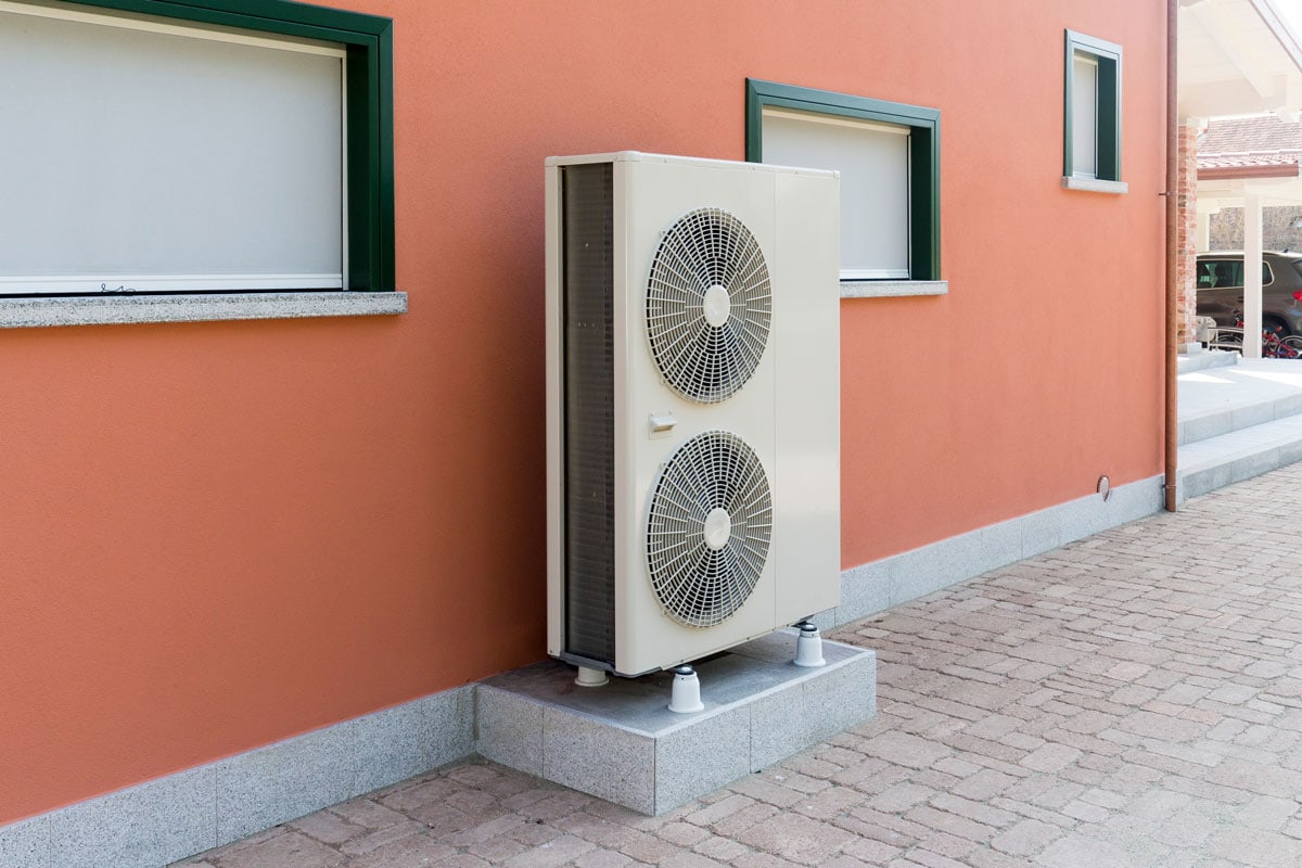 A tall double heat pump mounted on the side of a house