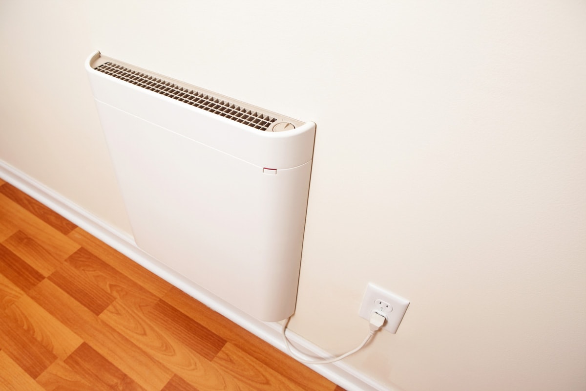 A wall-mounted electric convection heater in a house room. 