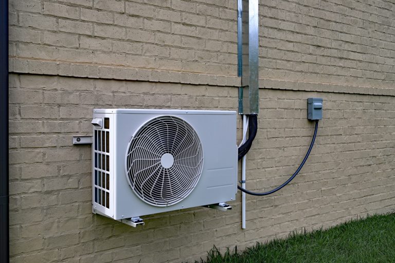 Air Conditioner mini split system next to home with painted brick wall and space - MrCool Vs Mitsubishi Mini Split: Which To Choose