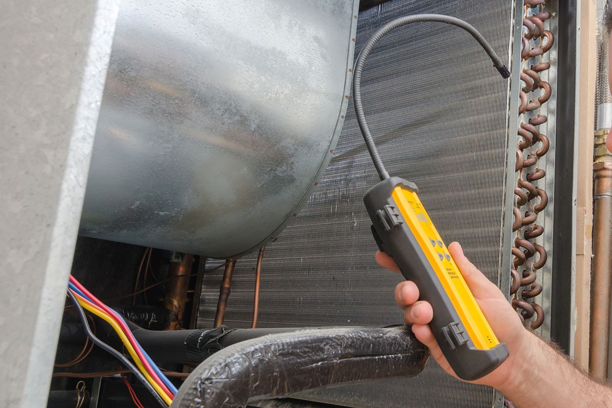 An Hvac technician searching for a refrigerant leak on an evaporator coil