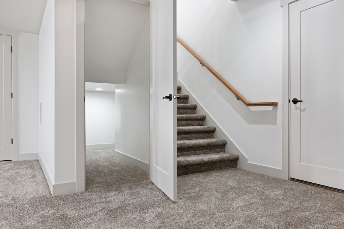 Carpeted basement flooring with white painted walls
