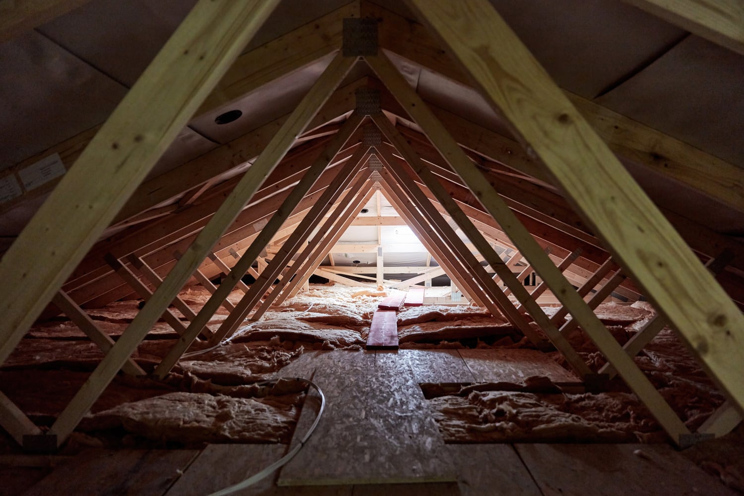 Dark attic with a small window and wooden beams in a new build house