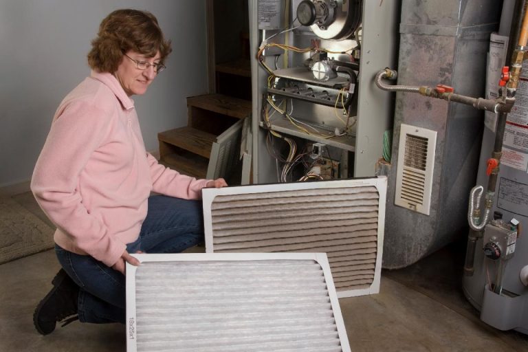 A homeowner inspects dirty air filters on furnace, Furnace Not Responding to Thermostat - What to Do?