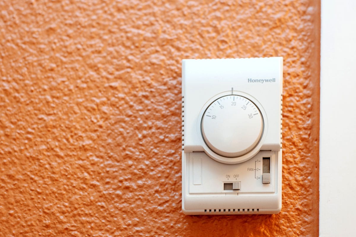 Honeywell thermostat mounted on an orange wall