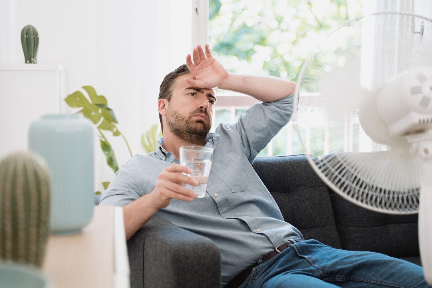 Man refreshing with electric fan against summer heat wave