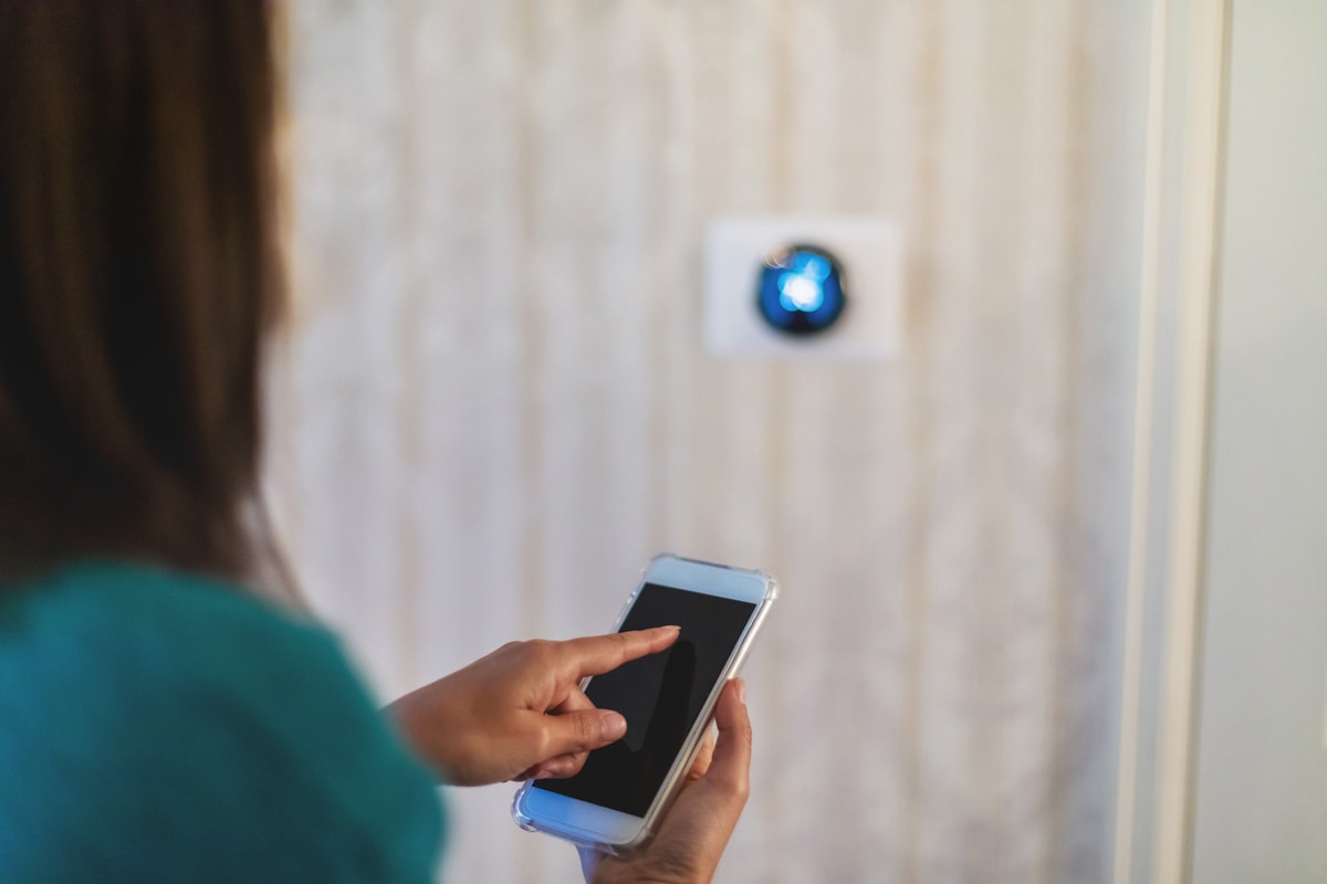 Millennial Female Using Smart Phone Technology to Adjust Thermostat Photo