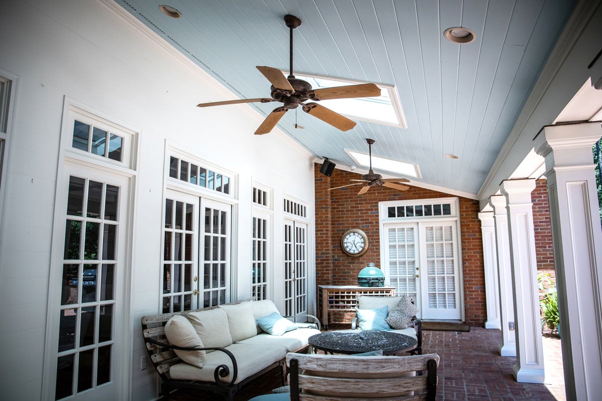 Outdoor back porch patio with outdoor seating and a large fan and table