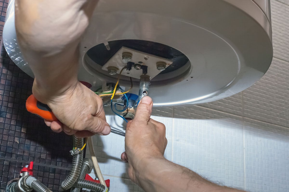 Repairman hand are fixing broken electric boiler