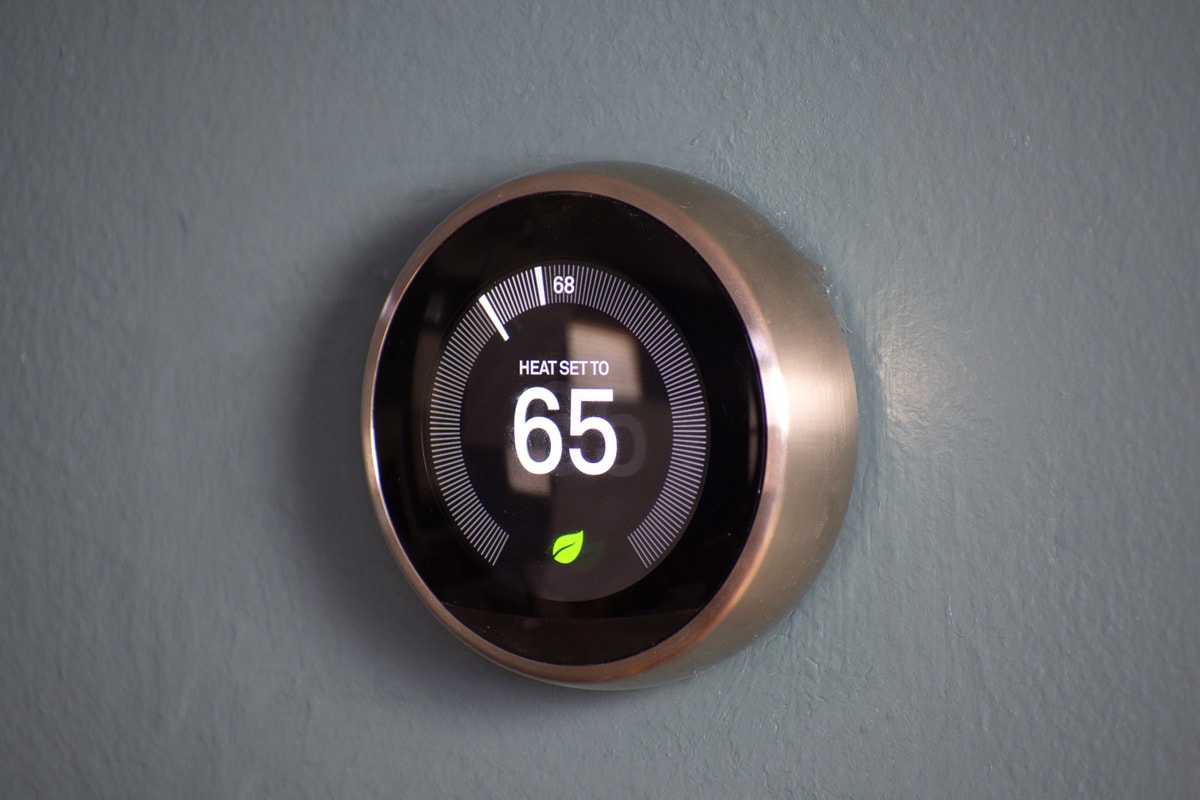 Smart home thermostat displaying temperature at an energy saving 65 degrees. Nest house temperature