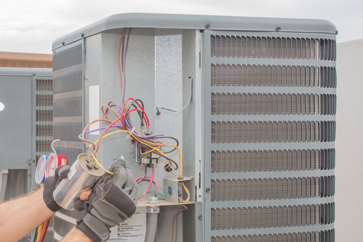 Technician changing the capacitor of the air conditioner