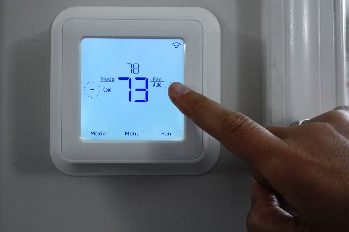 Thermostat peing adjust by a man touching the screen by a hand