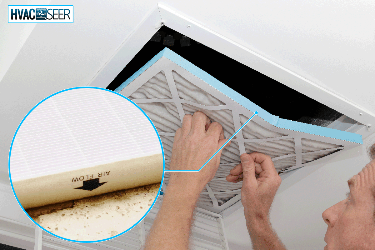 Person removing an old dirty air filter from a ceiling intake vent, Which Way Does An Air Filter Go In The Ceiling?
