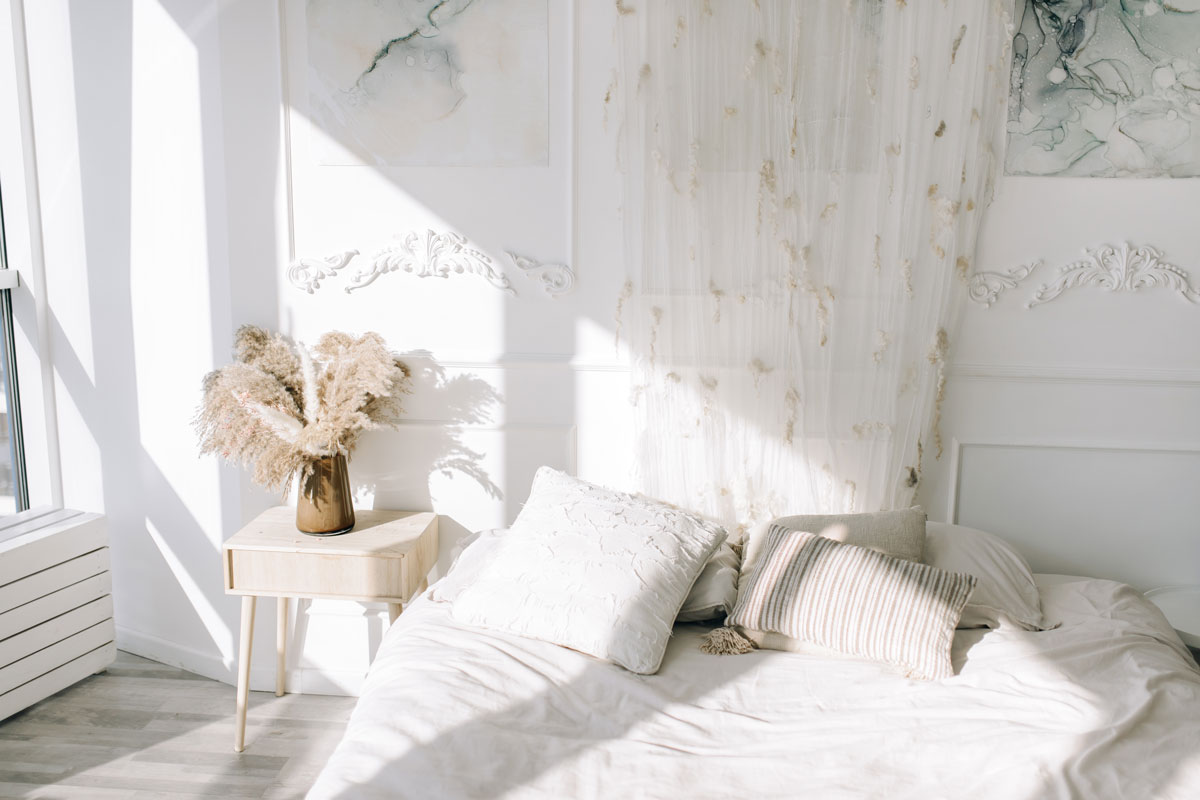 White inspired bedroom with a dried flower on the bedside table