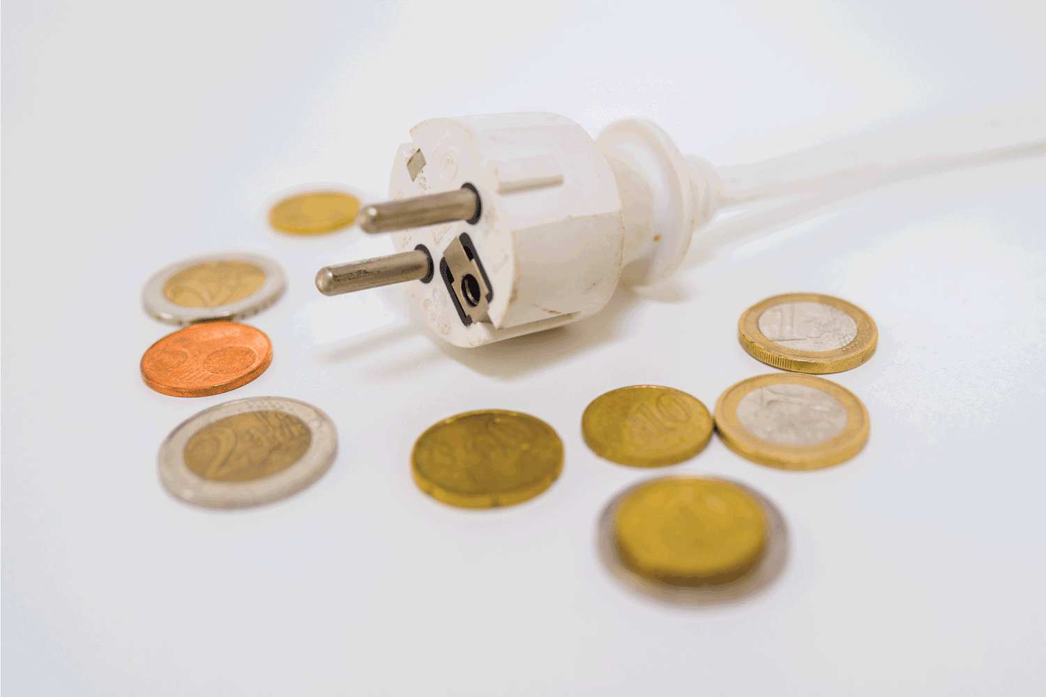 coins surrounding power cable plug, electricity costs concept