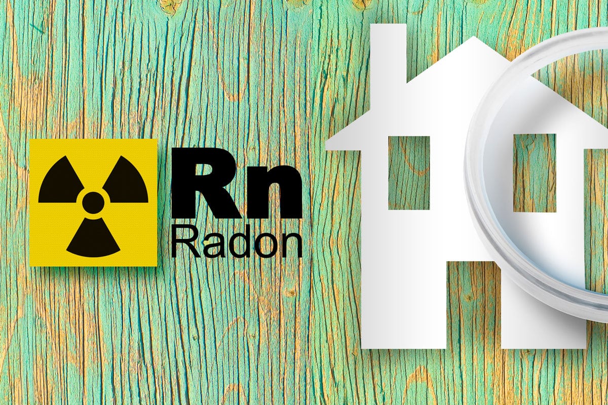 danger of radon gas in our homes - concept with periodic table of the elements, radioactive warning symbol and home silhouette seen throu