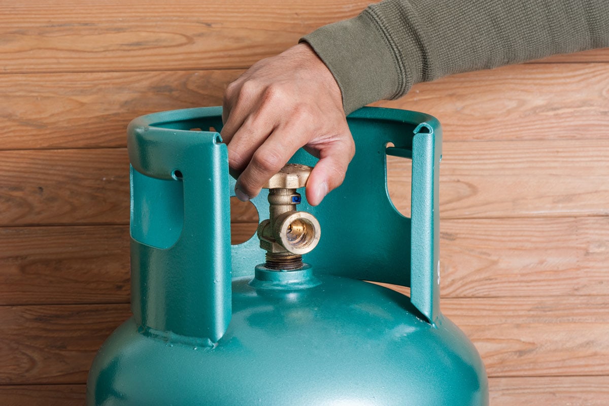 man's hand operating valve of LPG cylinder for cooking