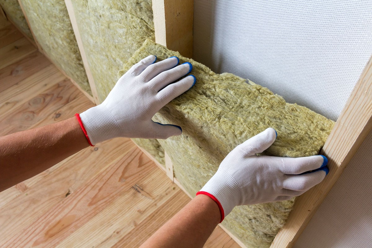 worker hands in white gloves insulating rock wool insulation staff in wooden frame for future walls for cold barrier