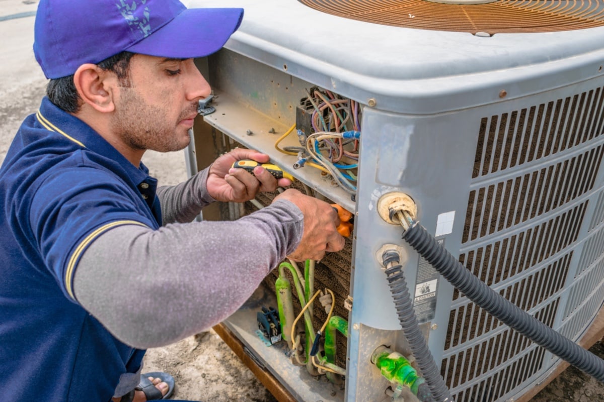 A Faulty Electric Control - a professional electrician man is fixing the heavy unit of an air conditioner